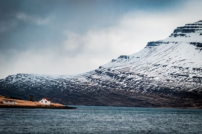 白天在白雪覆盖的山附近的岛上的房子